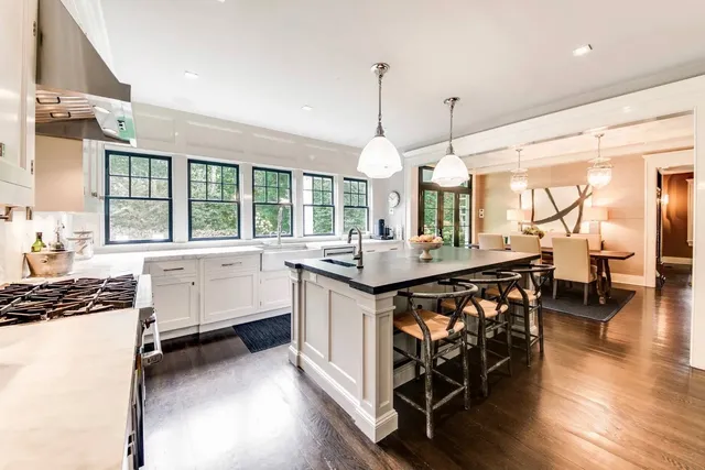 a kitchen with kitchen island granite countertop a stove a sink a dining table and chairs with wooden floor