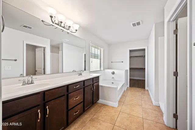 a spacious bathroom with a double vanity sink a large mirror and a bathtub