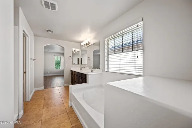 a bathroom with a tub a sink and a large mirror