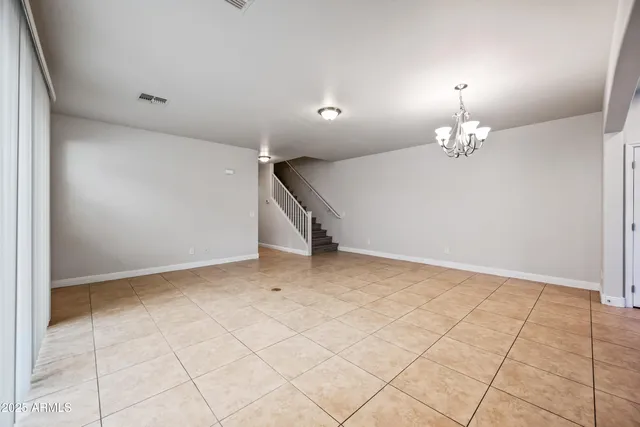 a view of an empty room with a chandelier fan