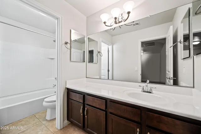 a bathroom with a granite countertop sink a toilet and a large mirror