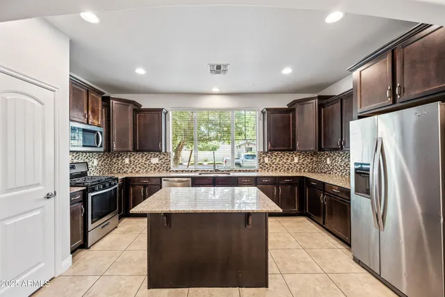 a large kitchen with stainless steel appliances granite countertop a stove sink refrigerator and cabinets