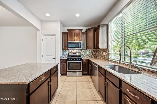 a kitchen with stainless steel appliances granite countertop a sink counter space cabinets and a large window