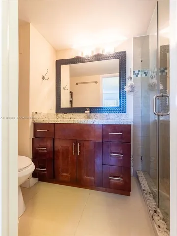 a bathroom with a granite countertop sink a mirror and a toilet