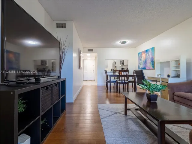 a large open kitchen with stainless steel appliances kitchen island granite countertop a table chairs in it and wooden floors