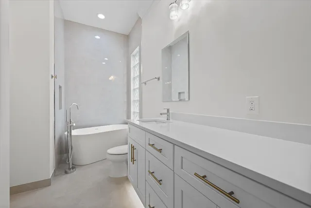 a bathroom with a granite countertop sink a toilet and bathtub
