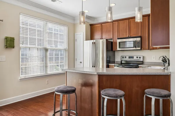 a kitchen with stainless steel appliances granite countertop a kitchen island hardwood floor and a sink