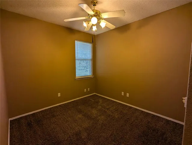 an empty room with a chandelier fan and a window