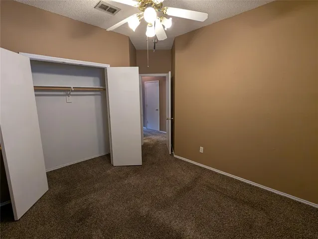 an empty room with a chandelier fan and closet