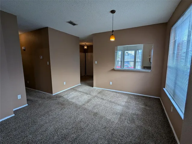 an empty room with chandelier fan and windows