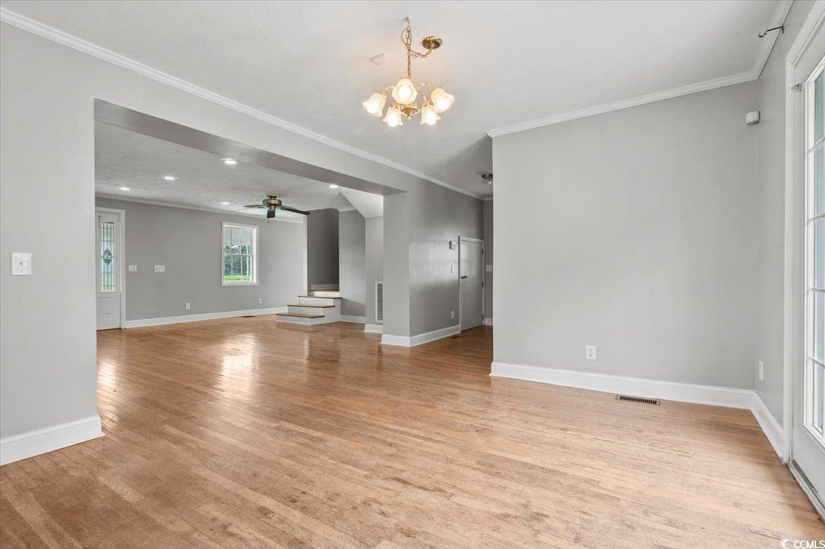 148 High Hill Road Lake View, SC 29563 - Photo 19 of 40 Unfurnished living room with ornamental molding, light wood finished floors, a chandelier, a ceiling fan, and stairs