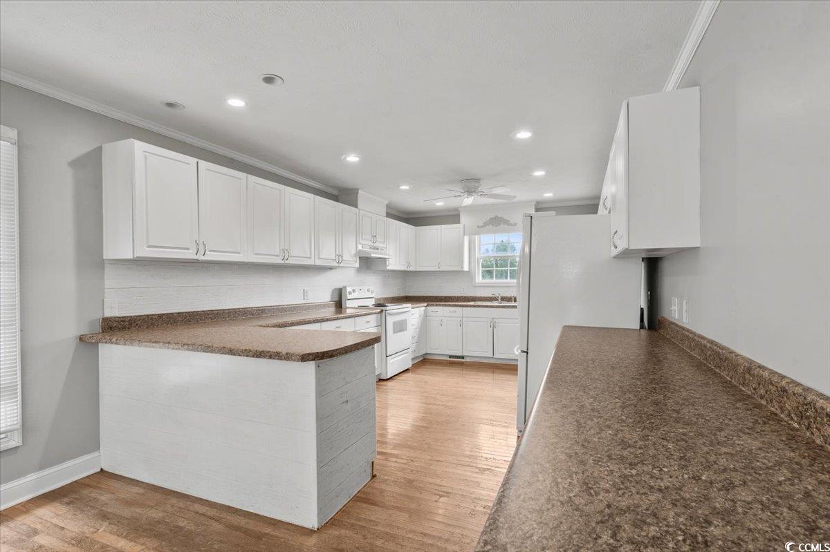 148 High Hill Road Lake View, SC 29563 - Photo 22 of 40 Kitchen featuring white cabinetry, white appliances, ornamental molding, dark countertops, and light wood-type flooring