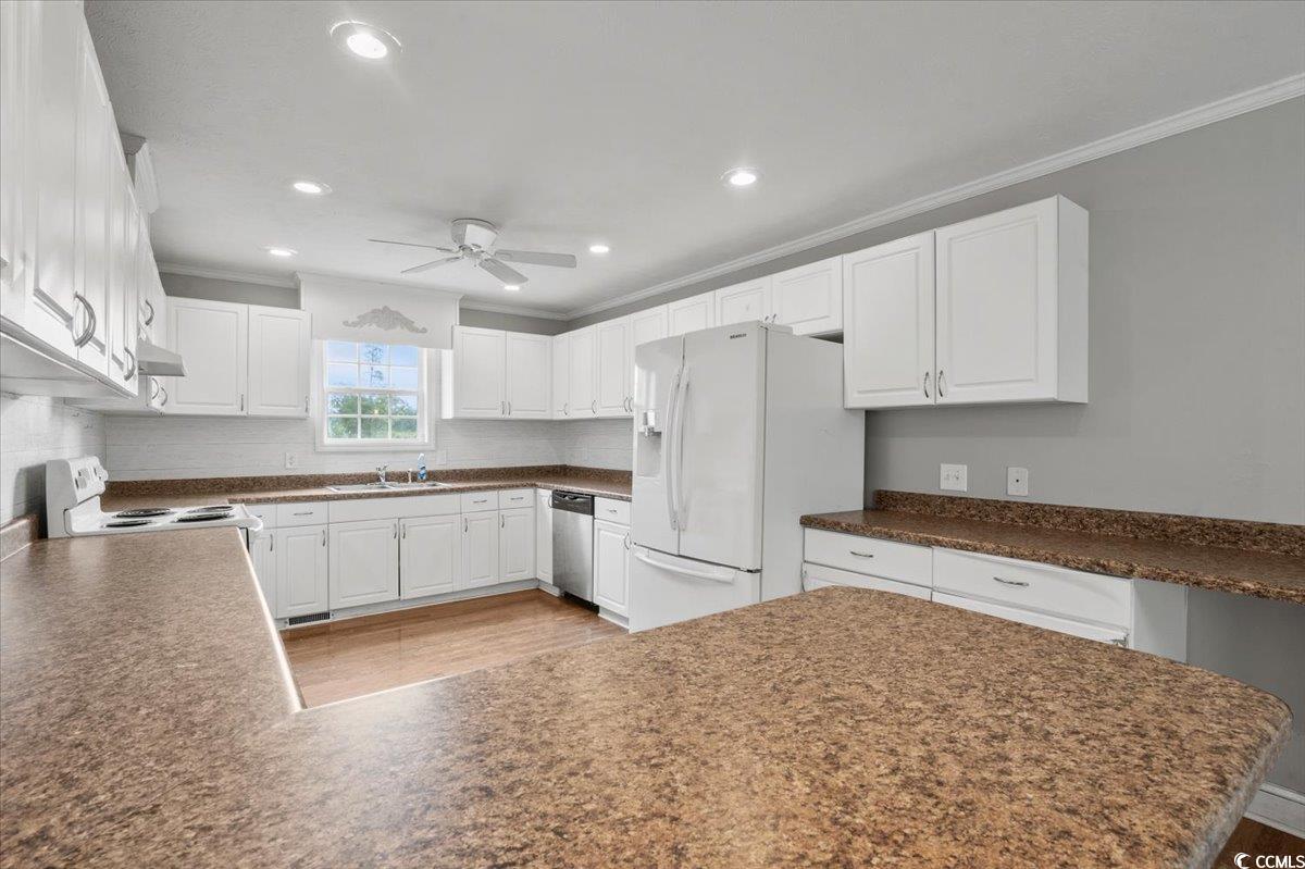 148 High Hill Road Lake View, SC 29563 - Photo 23 of 40 Kitchen featuring white cabinetry, ornamental molding, white appliances, wood finished floors, and dark countertops