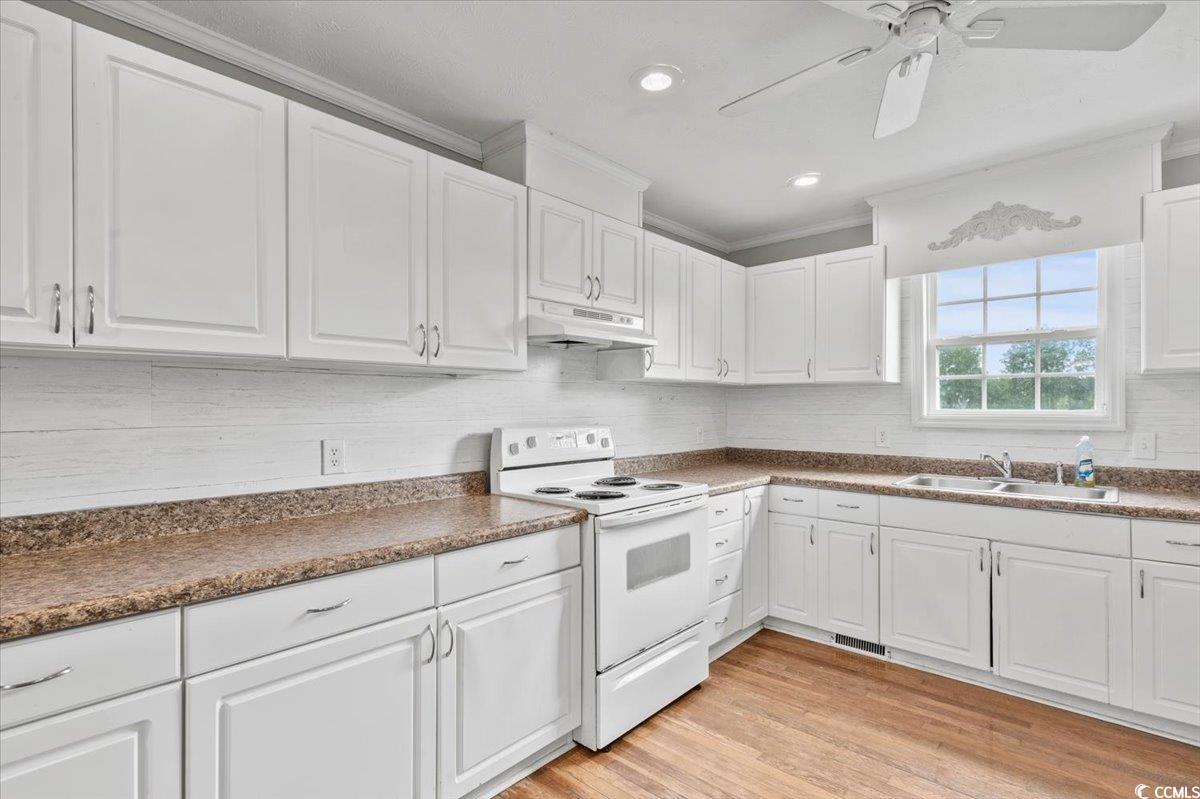 148 High Hill Road Lake View, SC 29563 - Photo 24 of 40 Kitchen featuring white cabinets, white electric range oven, light wood-style flooring, dark countertops, and ornamental molding