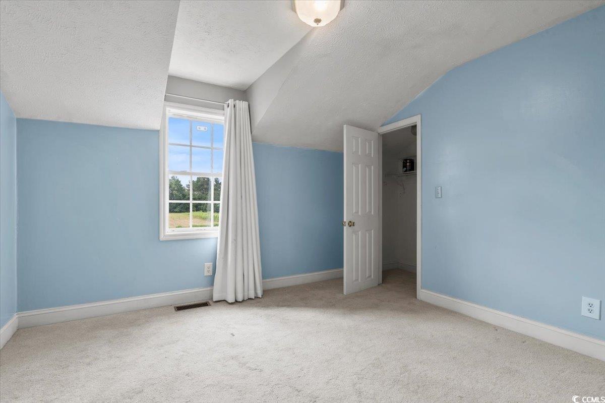 148 High Hill Road Lake View, SC 29563 - Photo 32 of 40 Additional living space with light carpet, a textured ceiling, and vaulted ceiling