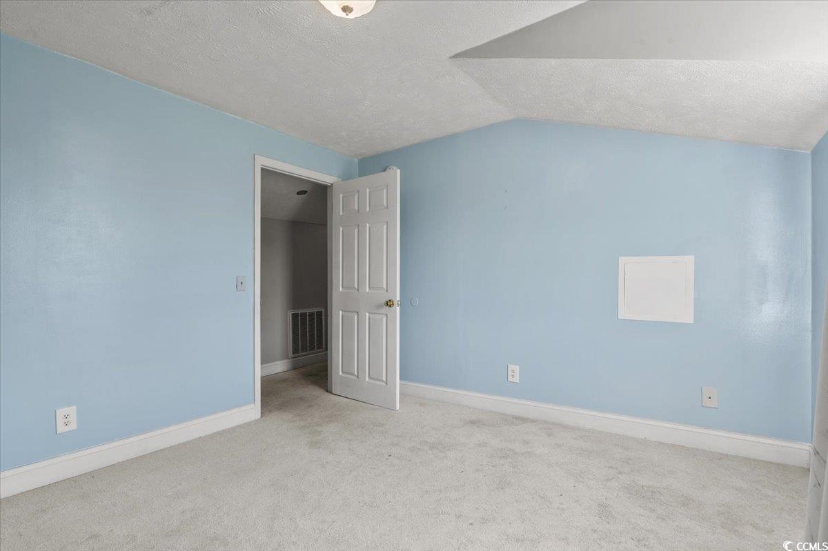 148 High Hill Road Lake View, SC 29563 - Photo 33 of 40 Unfurnished bedroom featuring a textured ceiling, carpet, and vaulted ceiling