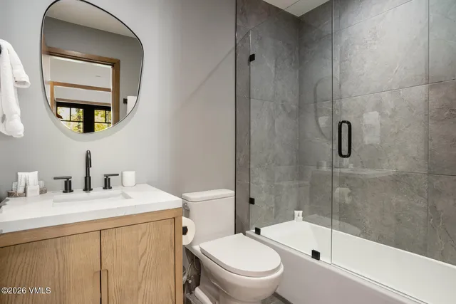 a bathroom with a toilet a sink a mirror a bathtub and shower