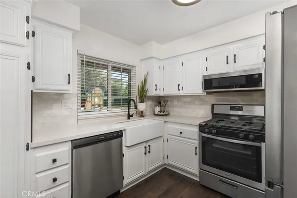 a kitchen with cabinets stainless steel appliances a sink and a window