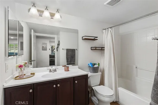 a bathroom with a sink a toilet a mirror a vanity and shower
