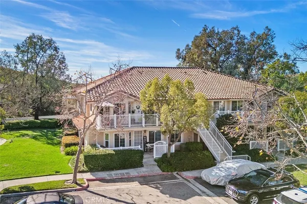 a view of a big yard in front of a brick house with large windows