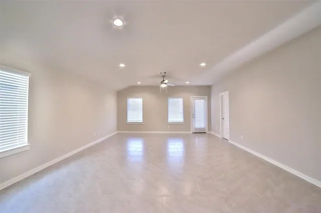 an empty room with windows and fan