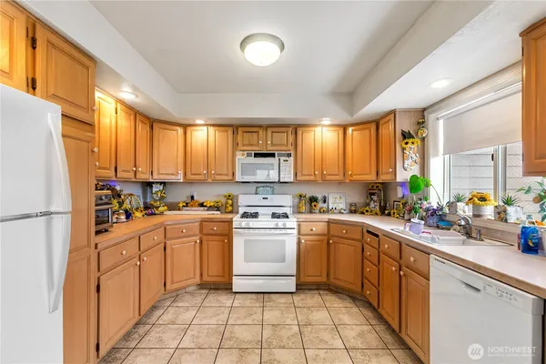a kitchen with a refrigerator a stove a sink dishwasher and white cabinets with wooden floor