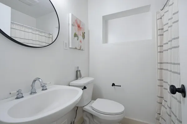 a bathroom with a sink a mirror a toilet and a shower