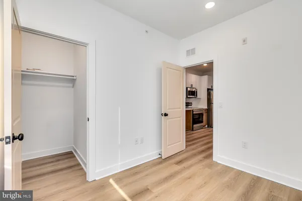 a view of a hallway with wooden floor and closet