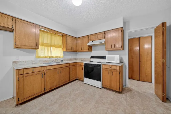 a kitchen with granite countertop a sink cabinets stainless steel appliances and a window