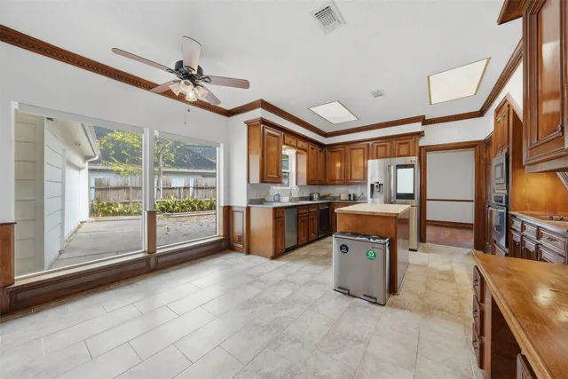 a view of a kitchen and dining area a chandelier fan windows