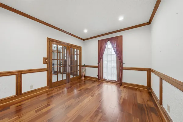 a view of empty room with wooden floor and fan