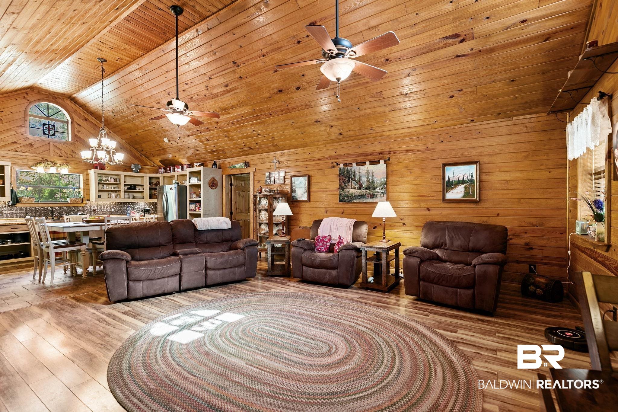 724 Rowell Lane Brewton, AL 36426 - Photo 9 of 40 Living area with high vaulted ceiling, a chandelier, light wood-style floors, wooden walls, and ceiling fan