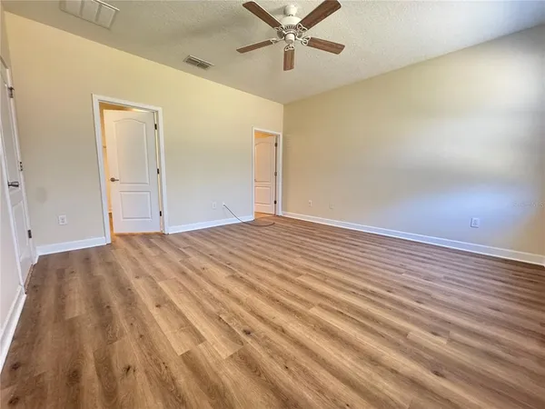 a view of a room with wooden floor and a ceiling fan