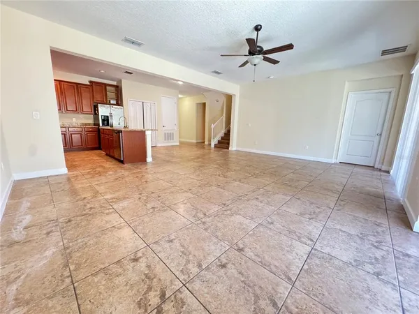 a view of a livingroom with a furniture a ceiling fan and kitchen view