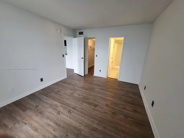 a view of an empty room with wooden floor and windows