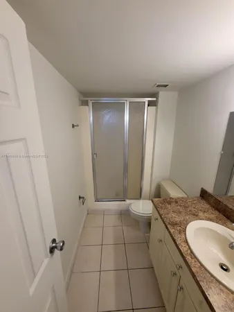 a bathroom with a granite countertop sink a mirror and a shower
