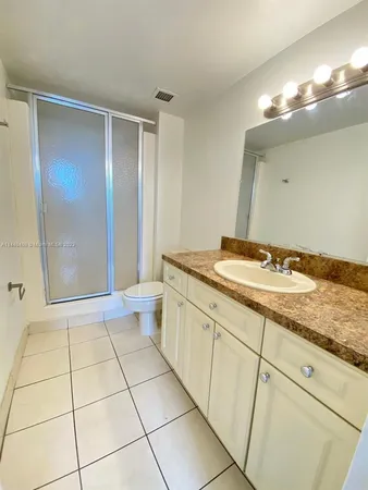 a bathroom with a granite countertop sink a toilet a mirror and shower