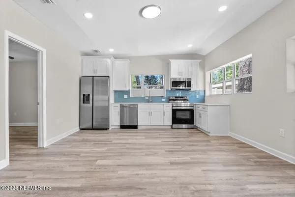 a view of an empty room with window and wooden floor