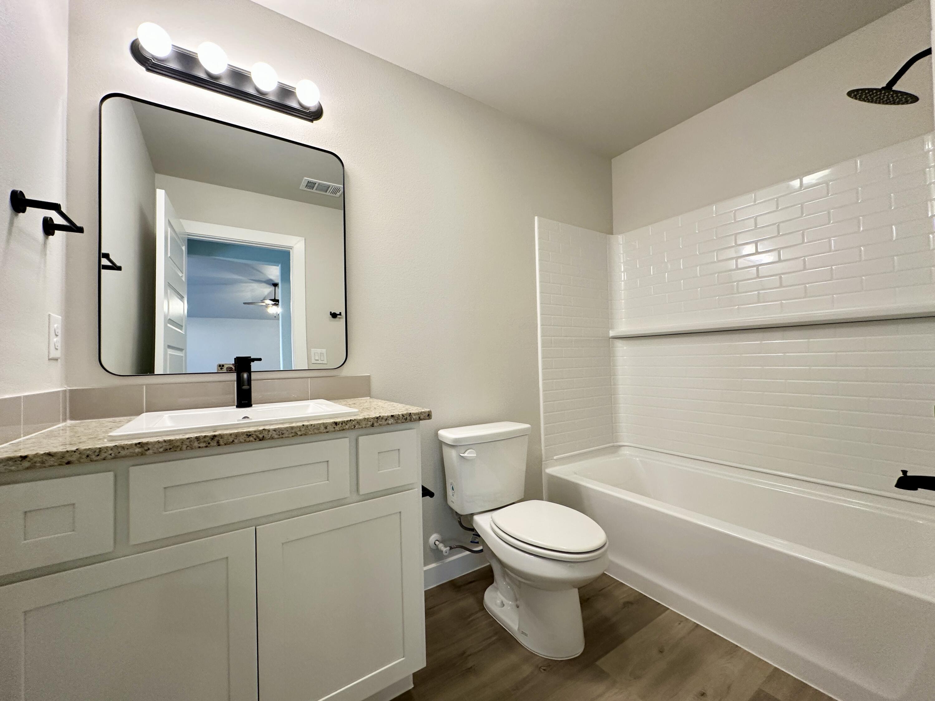 2208 134th Street Lubbock, TX 79423 - Photo 14 of 17 a bathroom with a granite countertop toilet sink and mirror