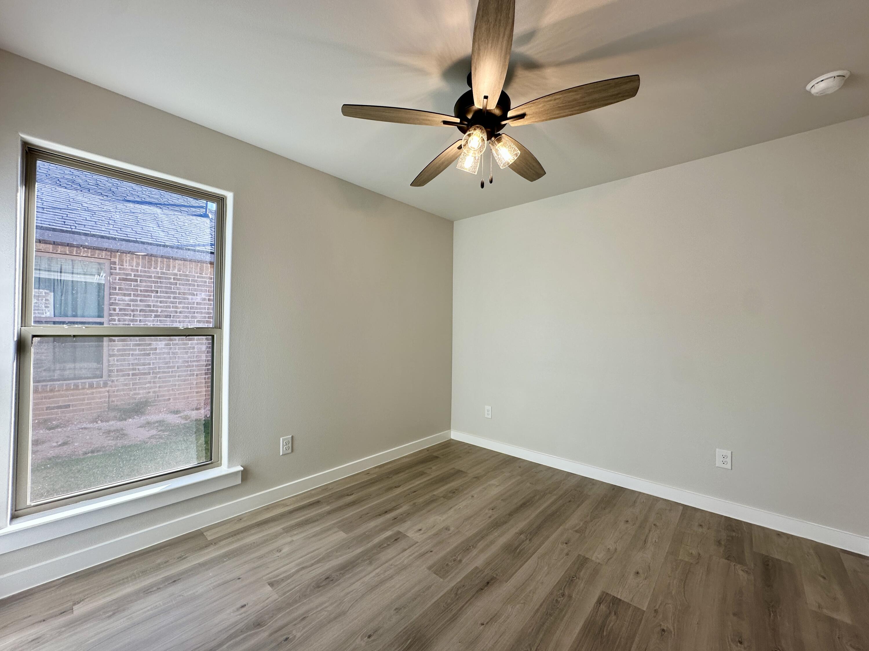 2208 134th Street Lubbock, TX 79423 - Photo 15 of 17 an empty room with wooden floor fan and windows