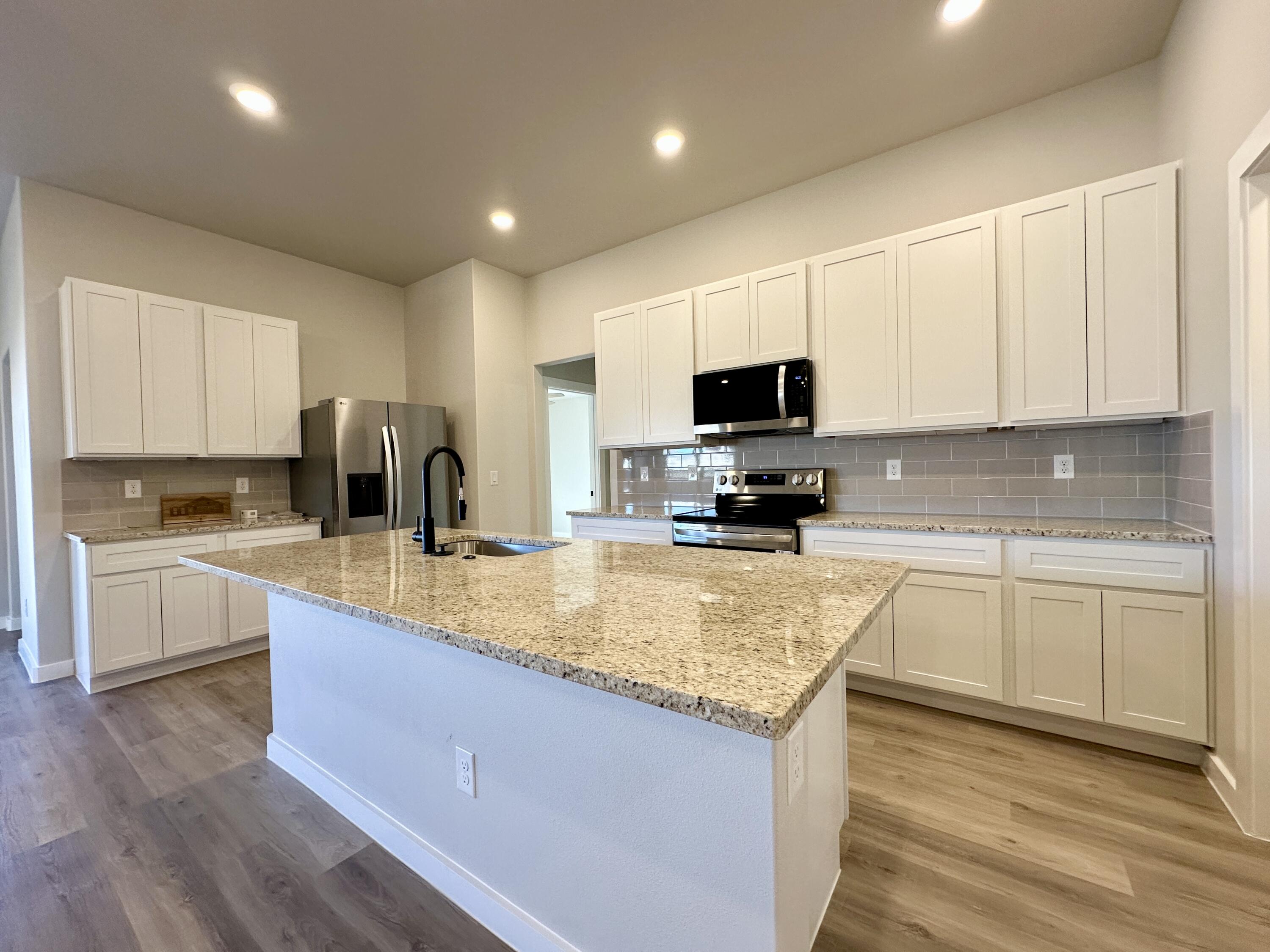 2208 134th Street Lubbock, TX 79423 - Photo 4 of 17 a kitchen with granite countertop a sink a counter top space stainless steel appliances and cabinets