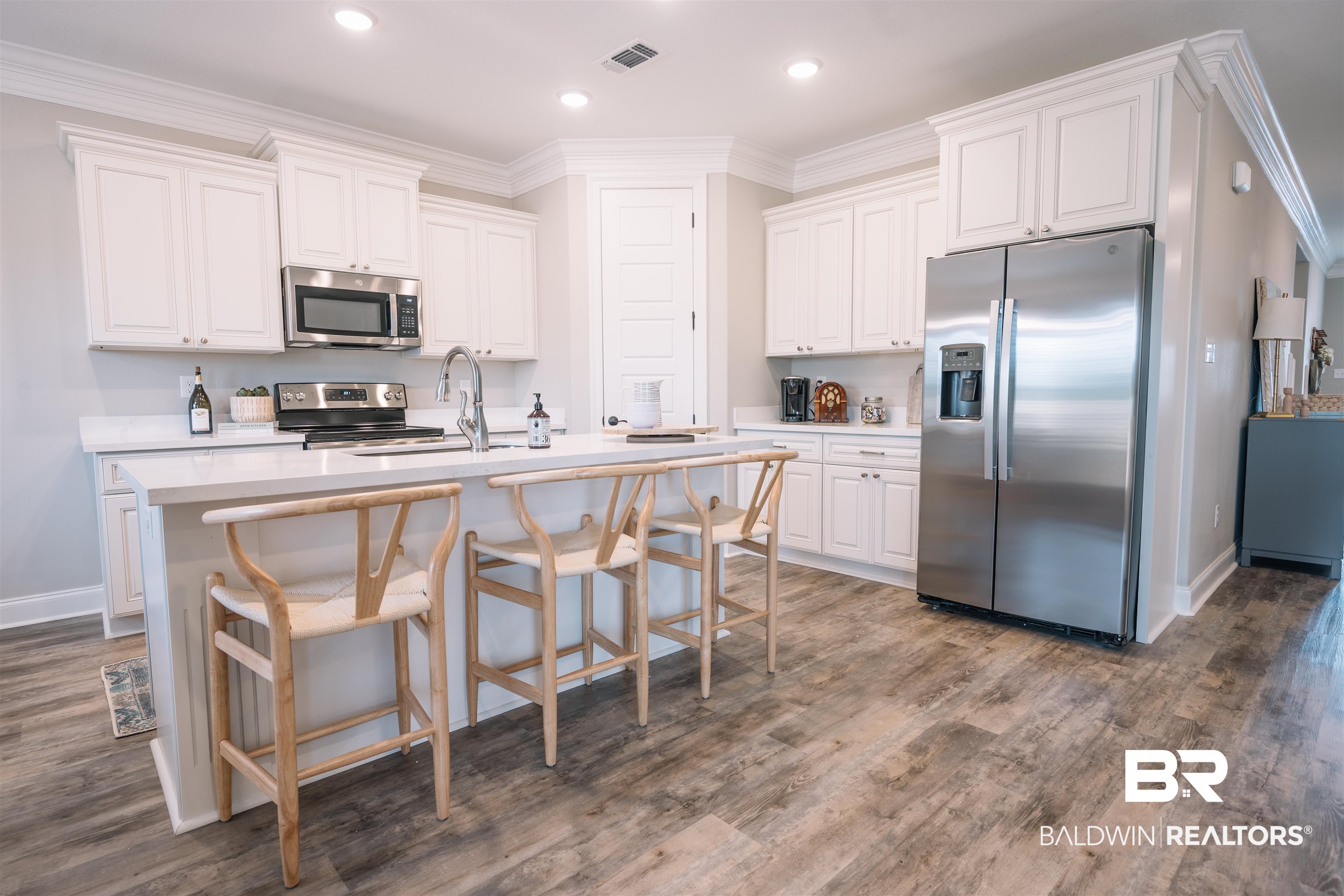 12894 Flanagan Street Elberta, AL 36530 - Photo 11 of 29 Kitchen with appliances with stainless steel finishes, white cabinetry, dark hardwood / wood-style floors, and a kitchen island with sink