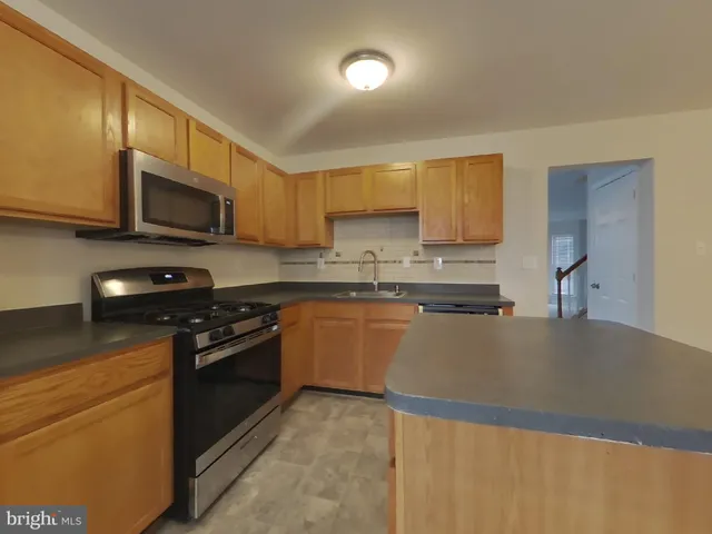 a kitchen with stainless steel appliances granite countertop a stove a sink and a microwave
