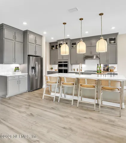a kitchen with stainless steel appliances kitchen island granite countertop a table chairs and a refrigerator
