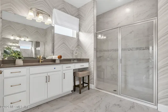 a bathroom with a granite countertop sink a mirror and a shower
