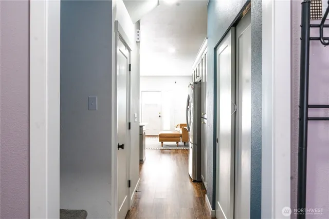 a view of a hallway with wooden floor and a bathroom