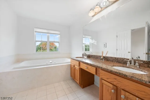 a bathroom with a granite countertop bathtub a sink and a window