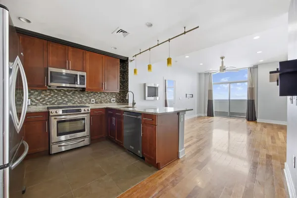 a large kitchen with stainless steel appliances granite countertop a stove top oven a sink and dishwasher