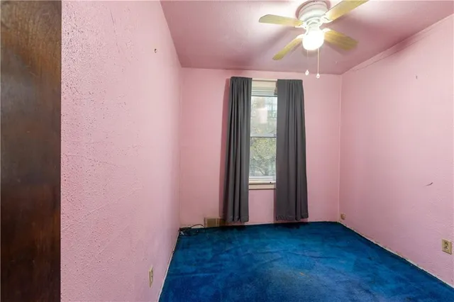 an empty room with a ceiling fan and a window