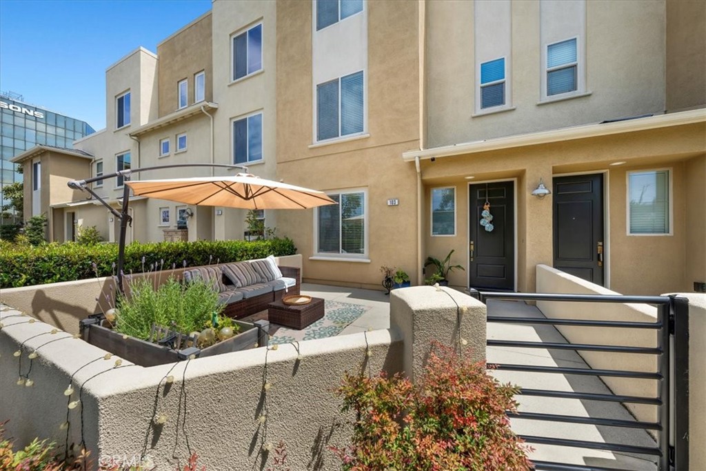 5565 Ocean, Unit 103 Hawthorne, CA 90250 - Photo 2 of 56 a view of a patio with couches table and chairs under an umbrella with a fire pit